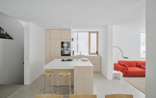 a kitchen with an island with stools and a red couch at Urban Mountain Splitlevel with Lake View in Maurach
