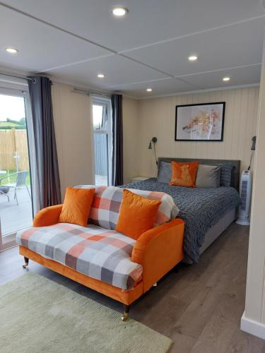 um quarto com uma cama e um sofá em The Den - Modern cabin with wood burning stove em Ludchurch