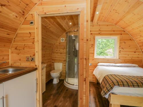 a log cabin bathroom with a bed and a sink at Pod 1 in Seascale