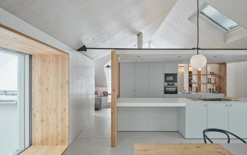 an open kitchen and dining room with white cabinets at Urban Alpine Penthouse with Lake View in Maurach