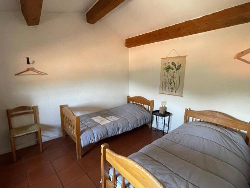 une chambre avec deux lits et une chaise dans l'établissement Gîte XL Familles et groupes Duilhac sous Peyrepertuse, à Duilhac-sous-Peyrepertuse