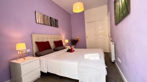 ein lila Schlafzimmer mit einem großen Bett mit weißer Bettwäsche und roten Kissen in der Unterkunft Apartamento Sants in Barcelona