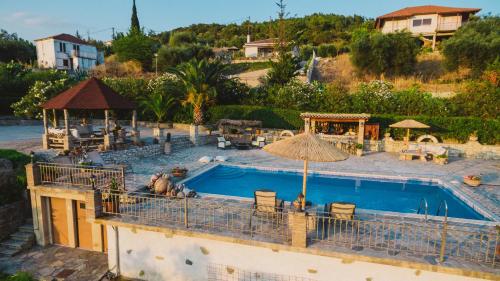 a swimming pool with chairs and an umbrella at Villa “Alexis&Coco” traditional house in Tríkorfon