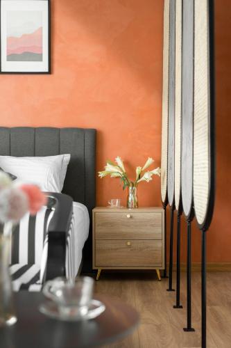 a bedroom with an orange wall and a bed and a table at De La Sol Villa Dalat in Da Lat
