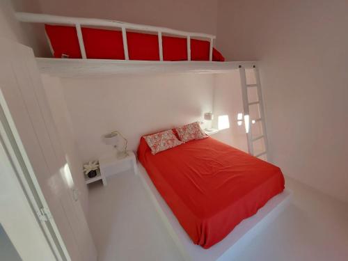 a small white room with a bed with red sheets at Casa Coral in São Marcos do Campo