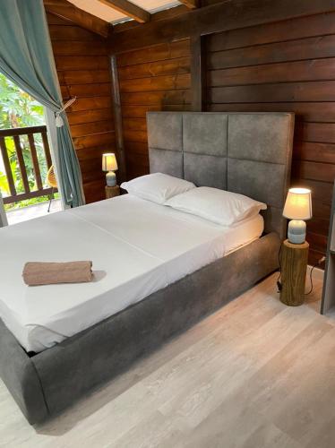 - une chambre avec un grand lit et des murs en bois dans l'établissement Verveine, à Vieux Bourg