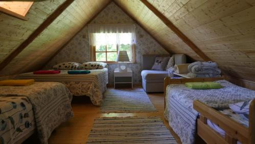 Cette chambre mansardée comprend deux lits et un canapé. dans l'établissement Veski Aida Holiday Home, à Käina
