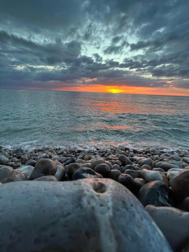 une plage rocheuse avec un coucher de soleil sur l'eau dans l'établissement QUAT, à Fécamp