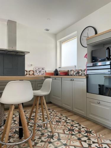 une cuisine avec deux chaises blanches et une horloge murale dans l'établissement Maison indépendante 