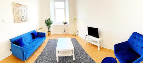 ein Wohnzimmer mit 2 blauen Sofas und einem TV in der Unterkunft The Snug in Dunoon