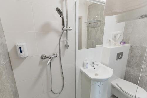 a white bathroom with a shower and a sink at Żabi Staw in Supraśl