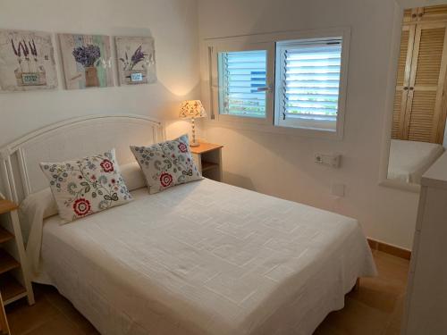 a bedroom with a white bed with two pillows at Casa Carmencita, immersa nel vede a due passi da mare in Es Calo
