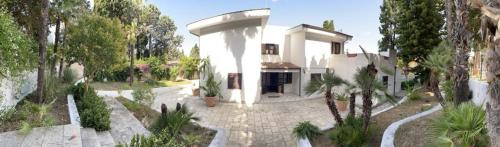 a large white house with a courtyard with trees at Relais LaValle in Taranto