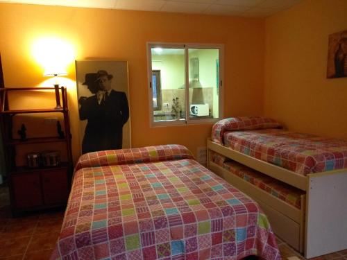a room with two beds and a picture of a man at La Casuca Azul in Ruiloba
