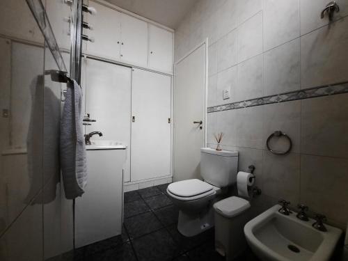 a white bathroom with a toilet and a sink at Casa c/amplio jardín, garage y parrilla. in Tandil