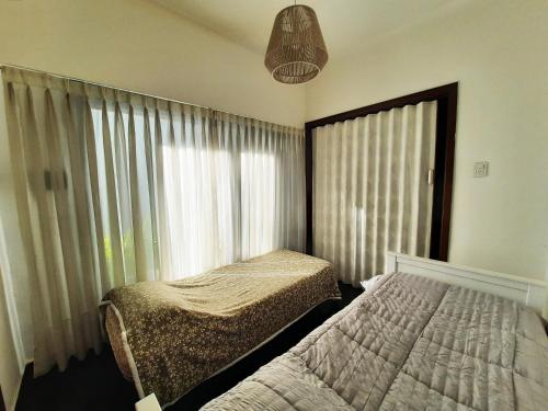 a bedroom with two beds and a window with curtains at Casa c/amplio jardín, garage y parrilla. in Tandil