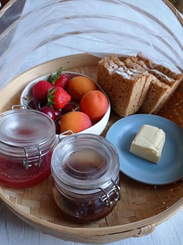 un plato de comida con fruta, pan y mantequilla en l'Annexe, logement confortable avec piscine, en Mazan