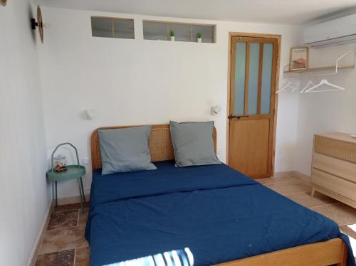 馬藏的住宿－l'Annexe, logement confortable avec piscine，一间卧室配有一张带蓝色床单的床和一张桌子。