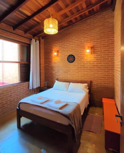a bedroom with a large bed in a brick wall at Encantos do Vale Pousada e SPA Cultural in Bueno Brandão