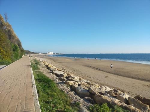 una spiaggia sabbiosa con persone che camminano su di essa di Estudio Guayaba cerca a la playa! a El Puerto de Santa María