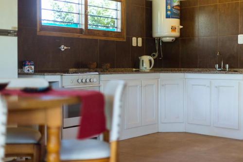 eine Küche mit weißen Schränken und einem Tisch mit einem roten Handtuch in der Unterkunft Alojamiento La Victoria in San Rafael