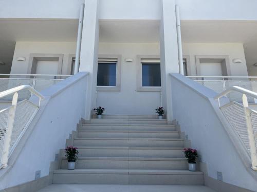 a staircase in a white building with potted plants at Curri Case al Mare in Monopoli