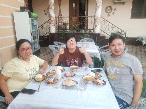 a group of three people sitting at a table with food at Imran&Bek in Samarkand