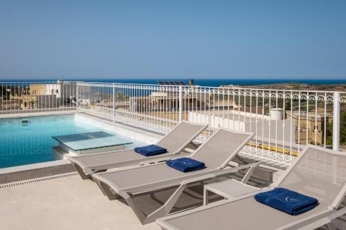 um pátio com 2 espreguiçadeiras e uma piscina em The Segond Hotel em Xagħra