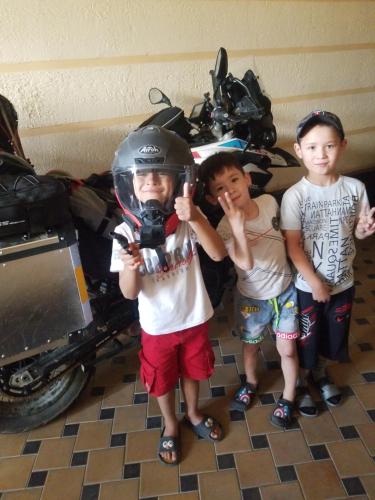 two boys are standing next to a motorcycle with a helmet at Imran&Bek in Samarkand