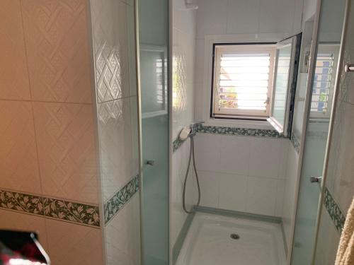 a bathroom with a shower and a window at Casa Carmencita, immersa nel verde a pochi passi da mare in Es Caló