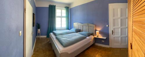 a bedroom with a bed with blue sheets and a window at Haus Kroneck-Salis Gästeappartement in Bad Iburg