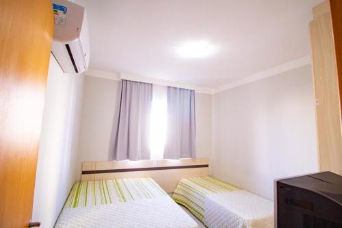 a small room with two beds and a window at Apart Hotel no Rio Quente- Cond. Águas da Serra in Rio Quente