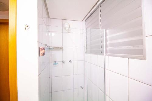 a bathroom with a shower with white tiles at Apart Hotel no Rio Quente- Cond. Águas da Serra in Rio Quente