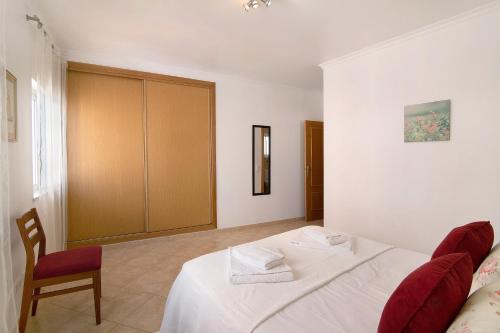 a bedroom with a white bed and a chair at Quarteira Beach iii in Quarteira