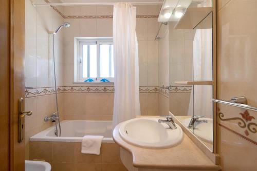 a bathroom with a sink and a tub and a shower at Quarteira Beach iii in Quarteira