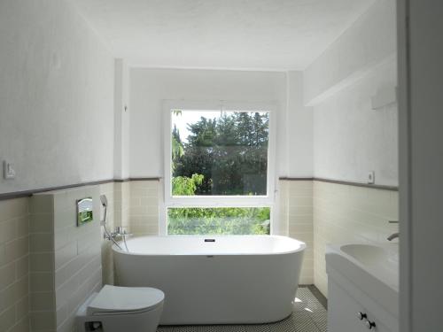 a bathroom with a tub and a toilet and a window at Ur La Maison in Urla