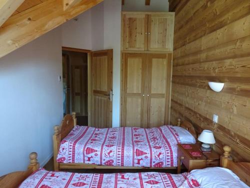 sypialnia z 2 łóżkami i drewnianą ścianą w obiekcie Chalet La Ruche w mieście Saint-Sorlin-dʼArves