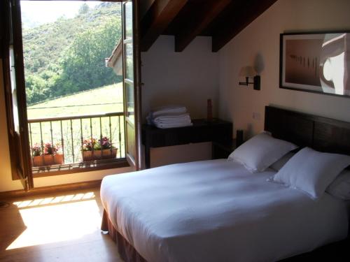 um quarto com uma cama grande e uma janela grande em La Cuétara de Linares em Ribadesella