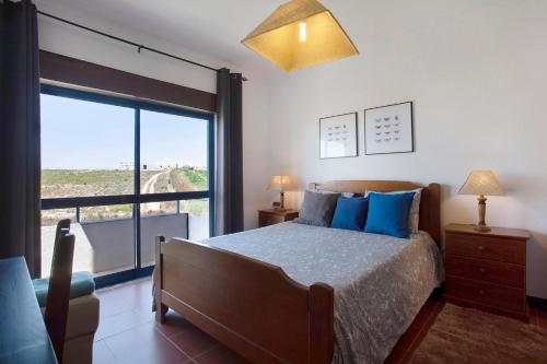 a bedroom with a bed and a large window at Sao Bernardino Beach House in Atouguia da Baleia