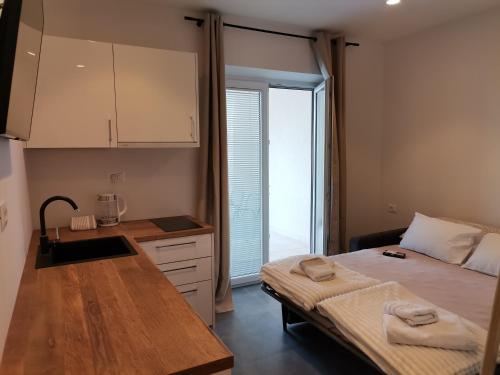 a bedroom with a bed and a kitchen with a counter at Mia & Ante Apartman in Tučepi