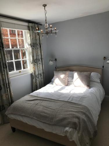 a bedroom with a bed with a chandelier and a window at Clerks Cottage in Upton upon Severn