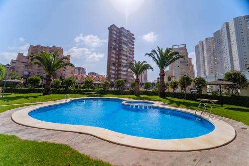 una piscina en un parque con palmeras y edificios en See the Sea Miramar apartment - 150m to the beach en Benidorm