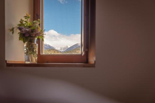 a window with a vase of flowers and mountains at Cal Calsot Casa Rural "Adults Only" in Montellá