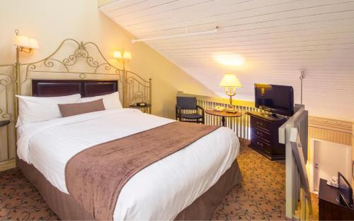 a hotel room with a large bed and a flat screen tv at Auberge Québec in Quebec City