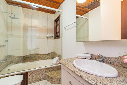 a bathroom with a sink and a tub and a toilet at Apto com banheira de imersão - Stay House in Canela