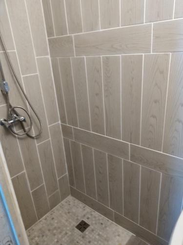 La salle de bains est pourvue d'une douche et de carrelage blanc. dans l'établissement Cute 1-bed cottage with view across park., à Issac