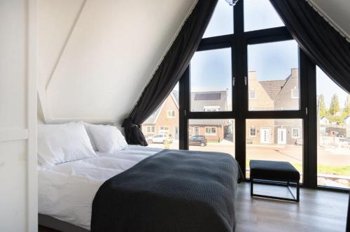 a bedroom with a bed and a large window at New high end waterfront family villa in Stavoren
