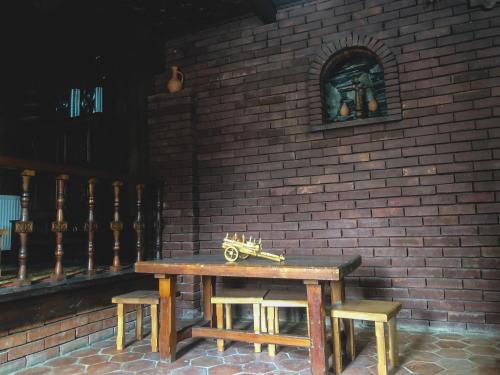 a wooden table and benches in front of a brick wall at Philia's Guest House in Sighnaghi