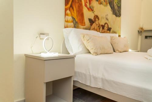 a bedroom with a white bed with a table and a painting at Il Loft di Quintino in Parma