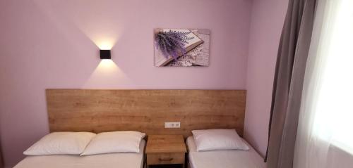 two beds in a room with a light on the wall at Motel Lavanda in Avşa Adası